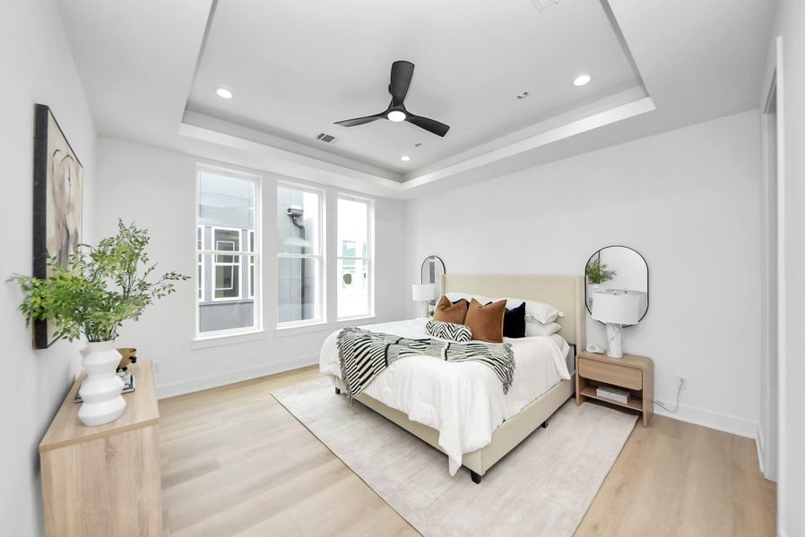 Primary bedroom located on the third floor with a tray ceiling and large windows.