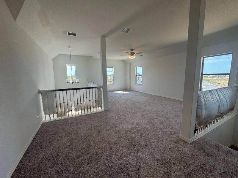 Empty room with carpet flooring, a chandelier, ceiling fan, and lofted ceiling
