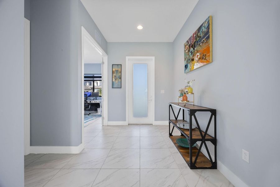 Corridor featuring a desk, light marble finish flooring, and recessed lighting