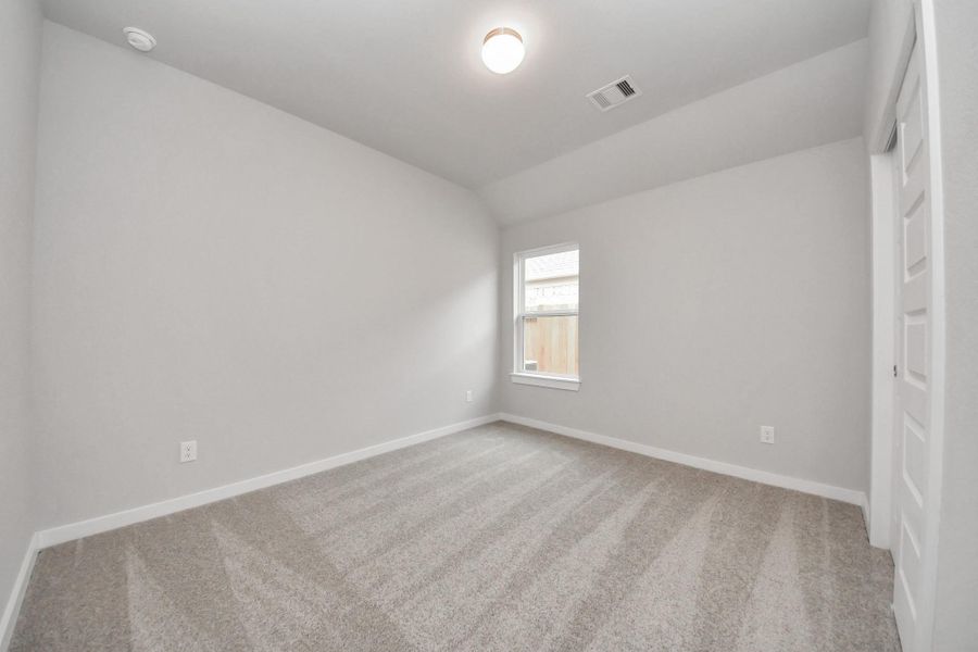 Secondary bedroom features plush carpeting, large windows that let in plenty of natural light, bright paint, and spacious closets. Sample photo of completed home with similar floor plan. Actual colors and selections may vary.