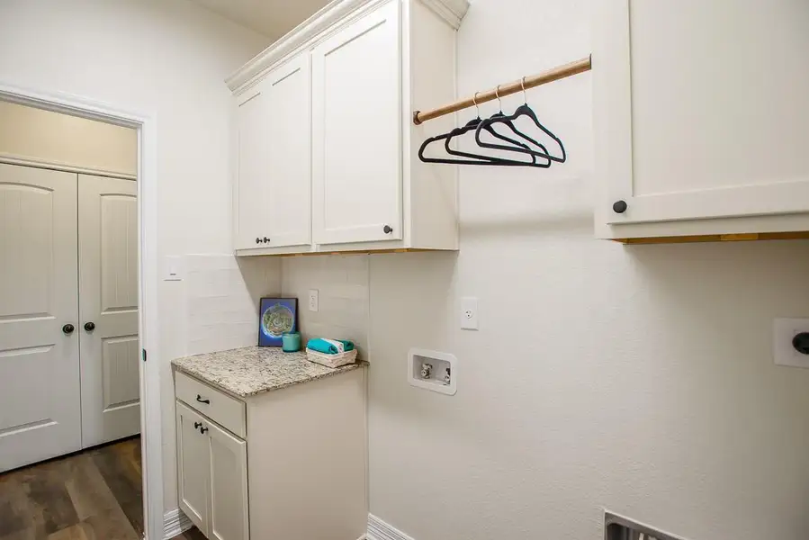 Laundry area featuring cabinet space, hookup for an electric dryer, washer hookup, and dark wood-type flooring Laundry area featuring cabinet space, hookup for an electric dryer, washer hookup, and dark wood-type flooring