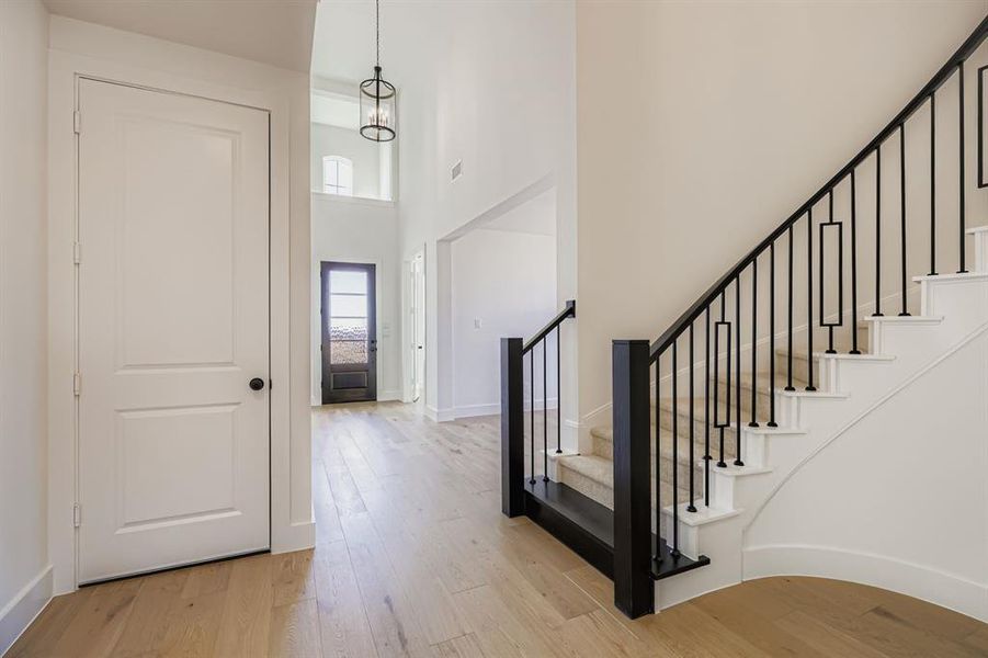 Entrance foyer featuring a towering ceiling, light wood-type flooring, and stairs