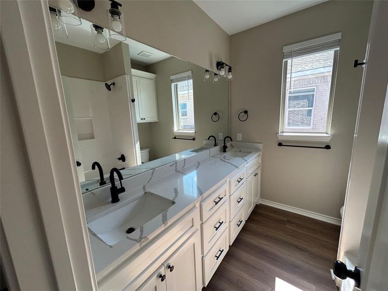 Bathroom with double vanity and dark wood-type flooring