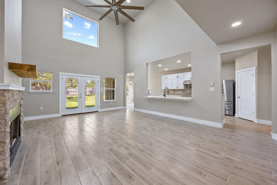 Unfurnished living room with light wood-style floors, baseboards, a ceiling fan, and a stone fireplace Unfurnished living room with light wood-style floors, baseboards, a ceiling fan, and a stone fireplace