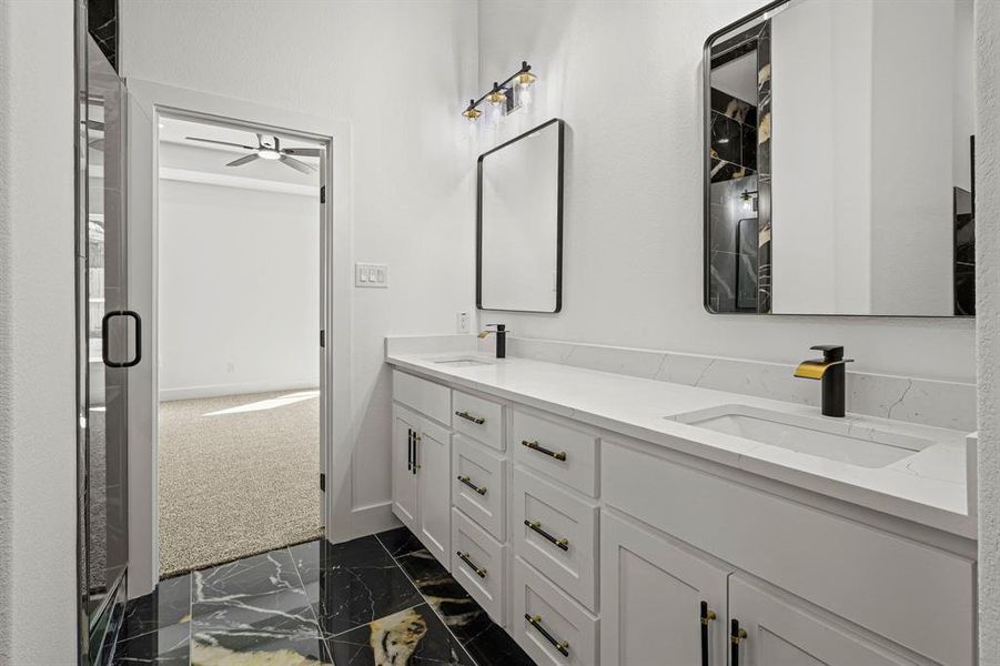 Bathroom with marble finish floor, a sink, baseboards, and double vanity