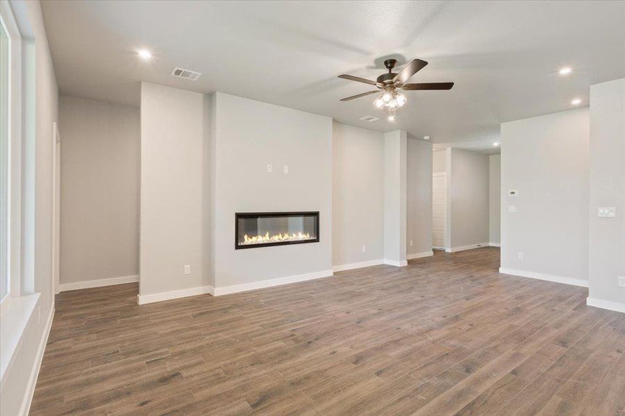 Unfurnished living room with recessed lighting, a glass covered fireplace, light wood-style flooring, and ceiling fan