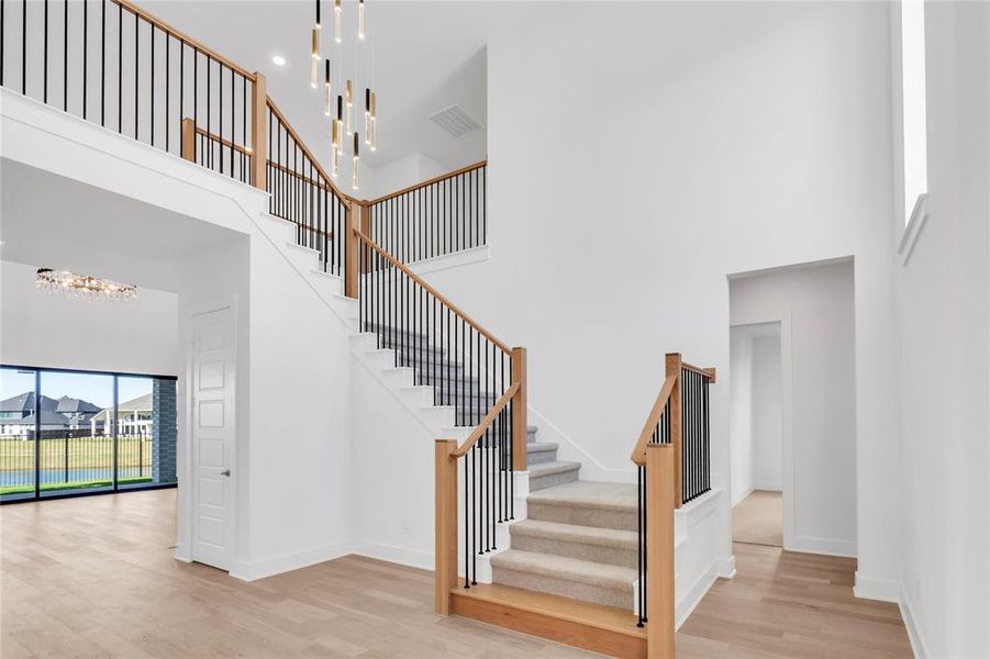 Staircase with a towering ceiling, wood finished floors, and a chandelier
