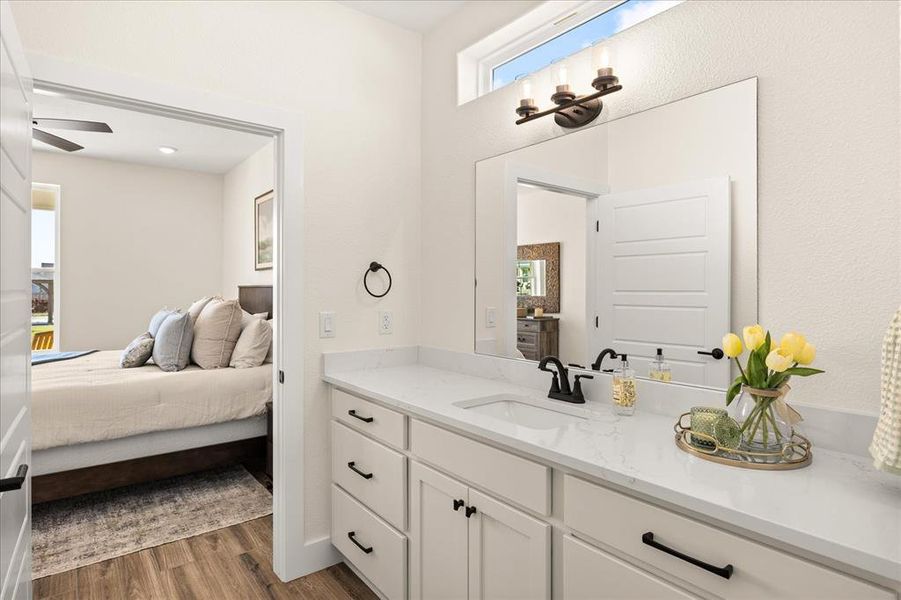 Bathroom vanity featuring a single undermount sink, a quartz countertop, and white cabinetry with black hardware