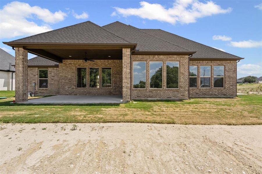 Rear view of property with ceiling fan, brick siding, a patio, and a lawn Rear view of property with ceiling fan, brick siding, a patio, and a lawn