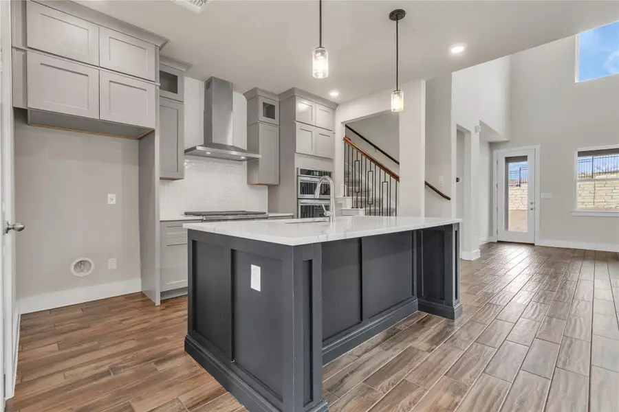 A well-appointed kitchen features a central island, recessed lighting, and rich wood flooring.