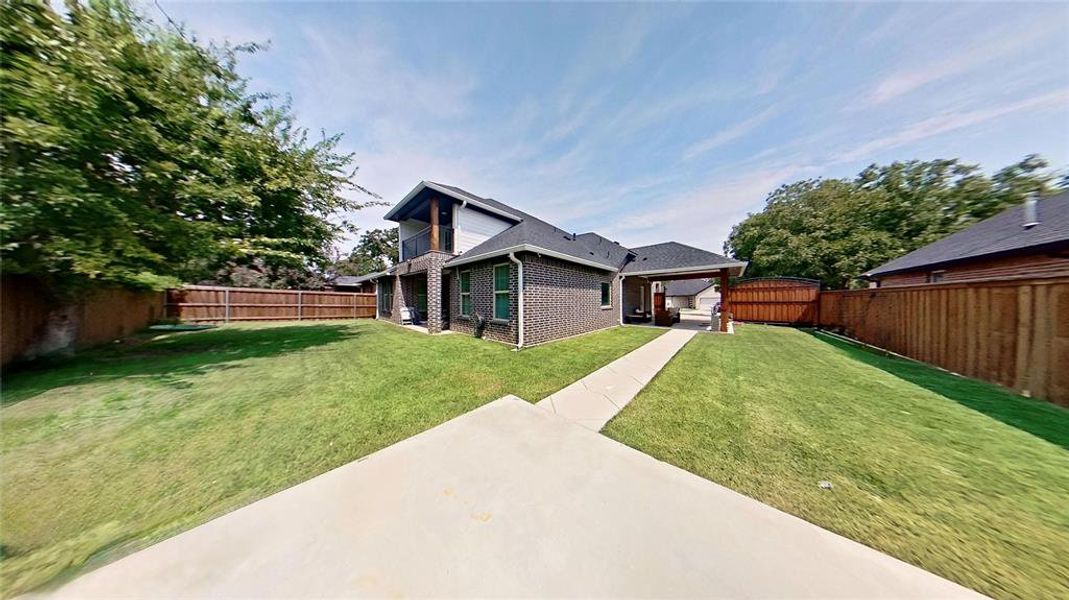 Back of house with a fenced backyard, brick siding, and a patio
