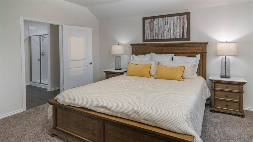 Bedroom featuring dark colored carpet, connected bathroom, and lofted ceiling