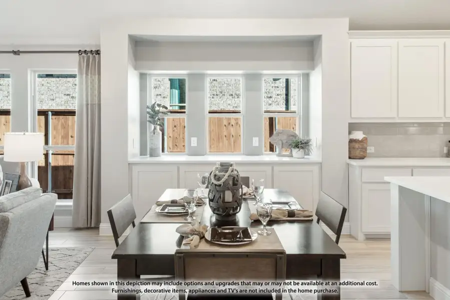Dining area with dark wood table, four chairs, and triple windows, open to kitchen with white cabinets and light wood floors