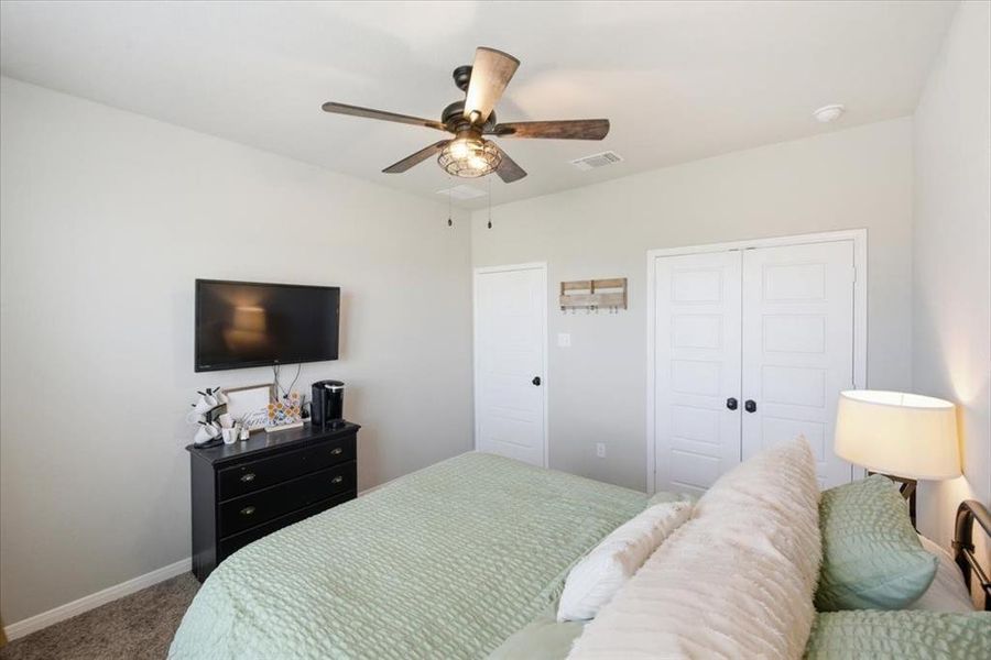 Spacious primary bedroom featuring carpet, ceiling fan, and a closet Spacious primary bedroom featuring carpet, ceiling fan, and a closet