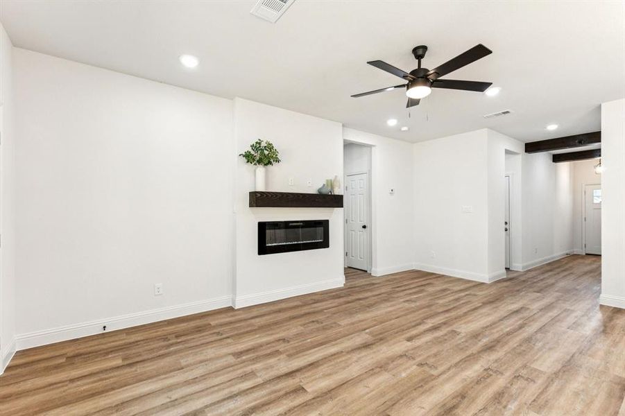 Unfurnished living room featuring a glass covered fireplace, light wood-type flooring, recessed lighting, and ceiling fan