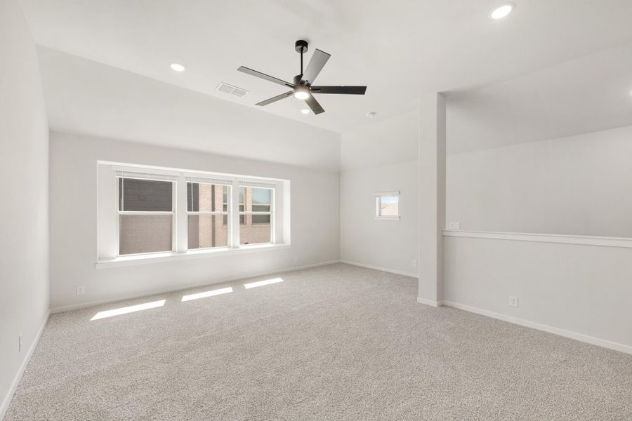 Empty bedroom with vaulted ceiling, ceiling fan, carpet flooring, and large windows