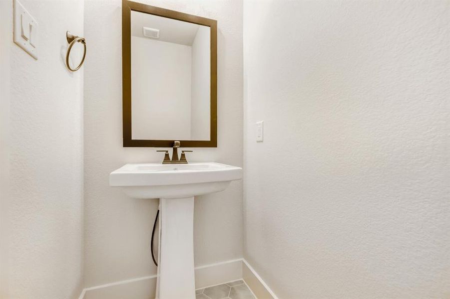 White pedestal sink with a bronze-framed mirror and matching bronze faucet