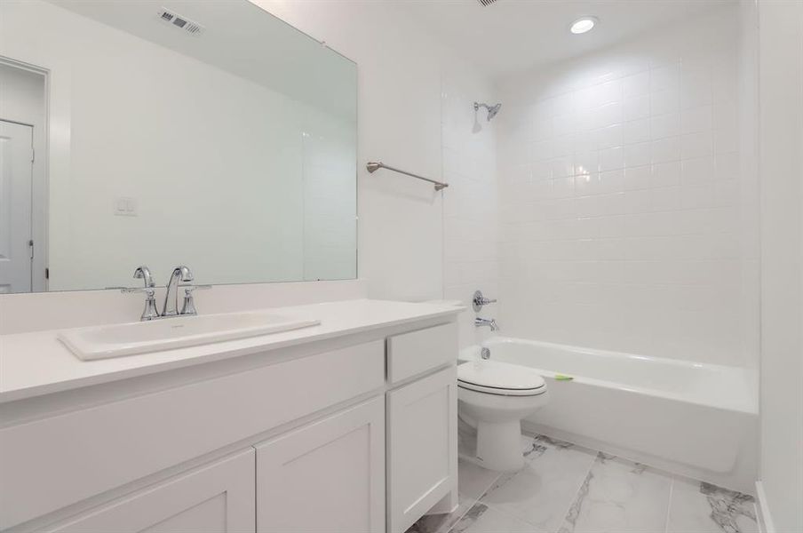 Full bathroom featuring vanity, tiled shower / bath combo, and toilet