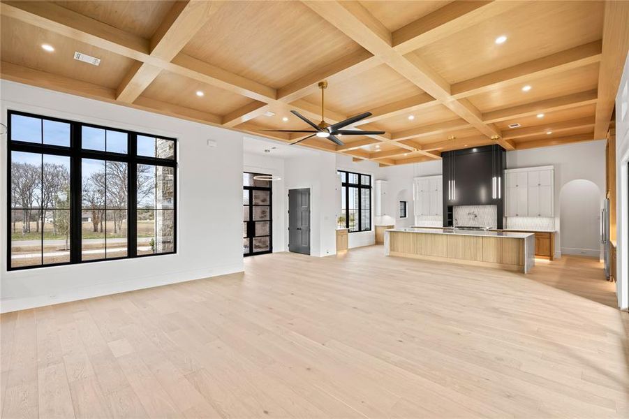 Unfurnished living room featuring ceiling fan, light wood-style floors, coffered ceiling, beam ceiling, and recessed lighting