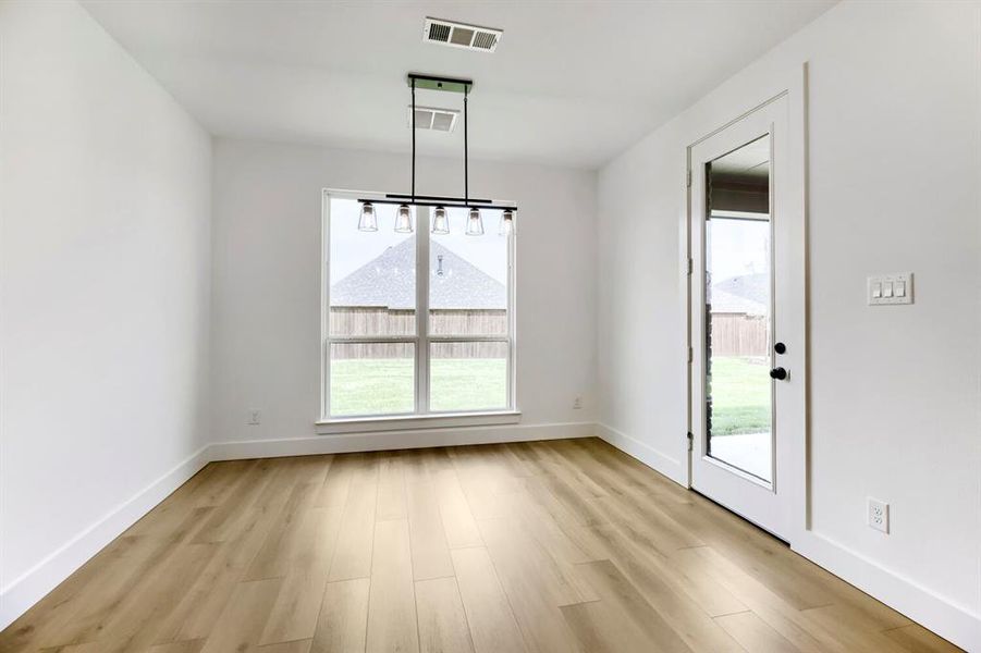 Dining area featuring wood-finish flooring, white walls, and a contemporary linear chandelier with five clear glass shades Dining area featuring wood-finish flooring, white walls, and a contemporary linear chandelier with five clear glass shades