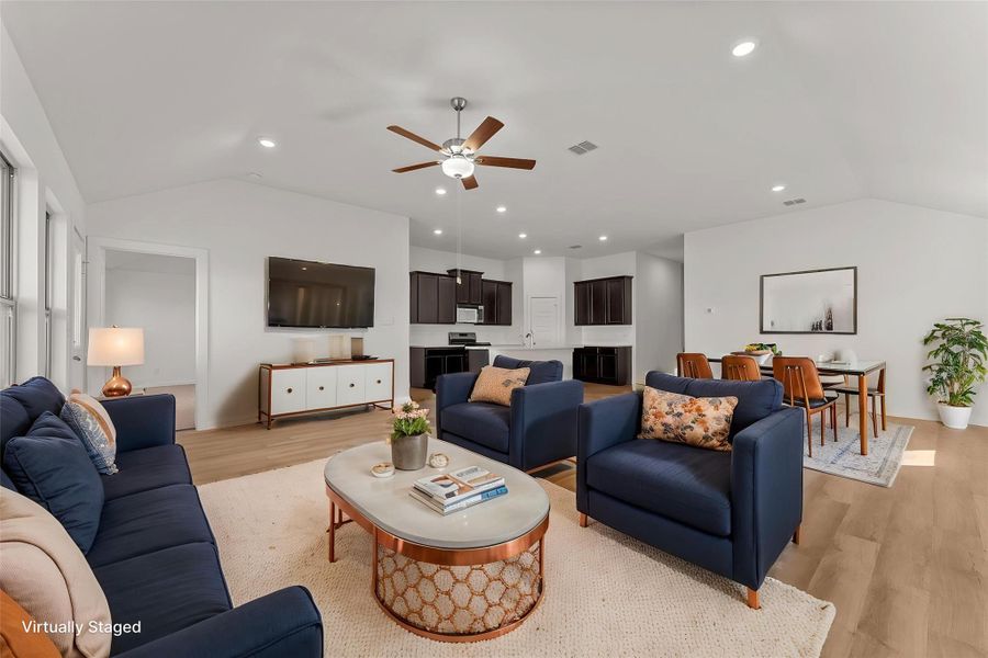 A vaulted ceiling living area boasts an open floorplan connecting seamlessly to the kitchen and dining space.