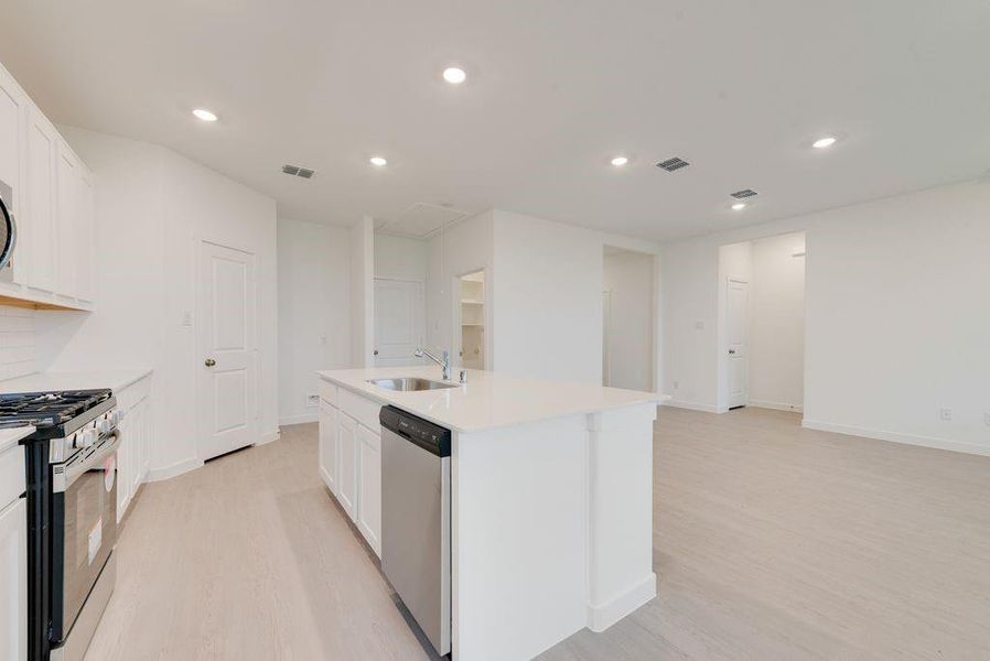 Kitchen with white cabinets, light wood finished floors, recessed lighting, appliances with stainless steel finishes, and a center island with sink Kitchen with white cabinets, light wood finished floors, recessed lighting, appliances with stainless steel finishes, and a center island with sink