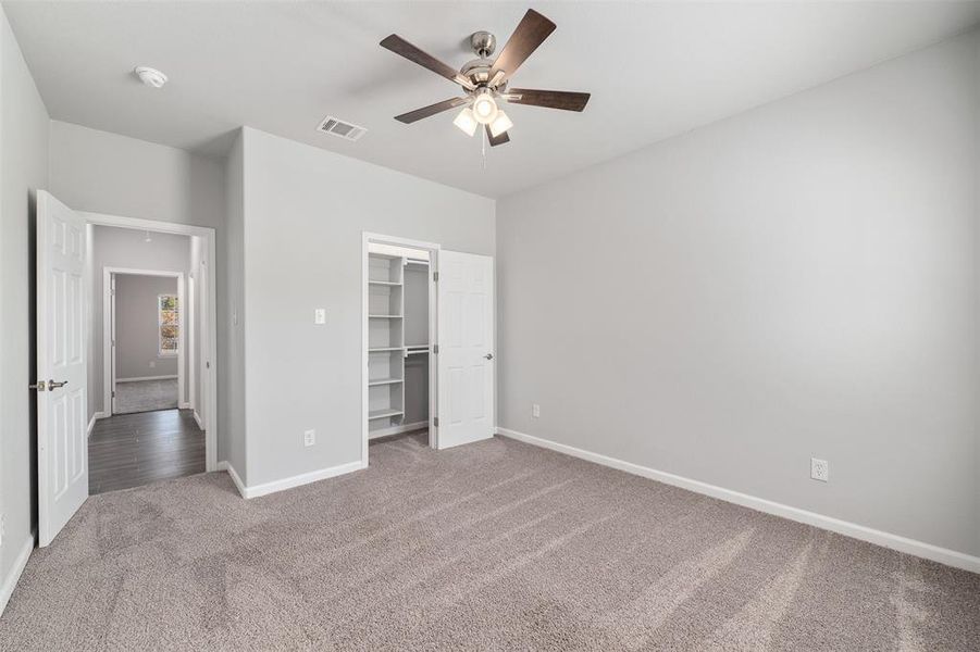 Unfurnished bedroom with a closet, a walk in closet, ceiling fan, and carpet flooring