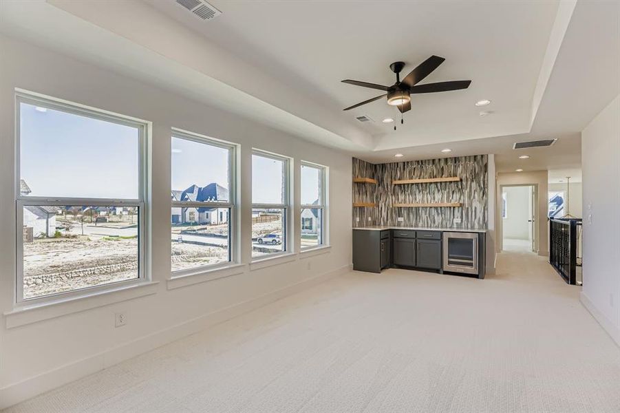 Indoor wet bar with light carpet, a tray ceiling, light countertops, wine cooler, and recessed lighting