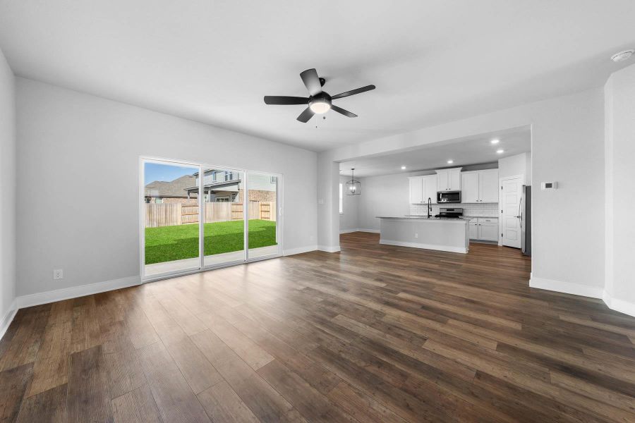 Unfurnished living room featuring hanging lights, a ceiling fan, and dark wood-style floors