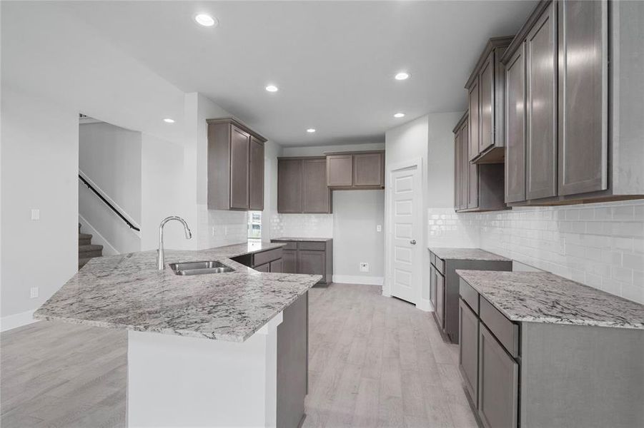 This stunning kitchen displays beautiful cabinets, custom neutral paint, granite countertops, light modern backsplash, and SS appliances, oversized kitchen with extra storage, breakfast bar, recessed lighting, high ceilings and pantry.