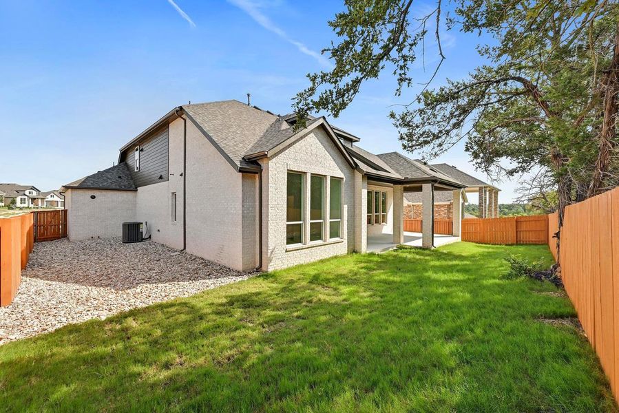 Back of house with a fenced backyard, brick siding, a patio, and roof with shingles