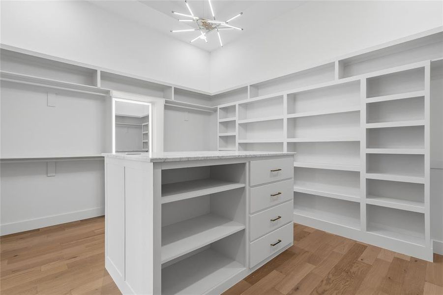 Expansive walk-in closet featuring a central island with a stone countertop and built-in drawers
