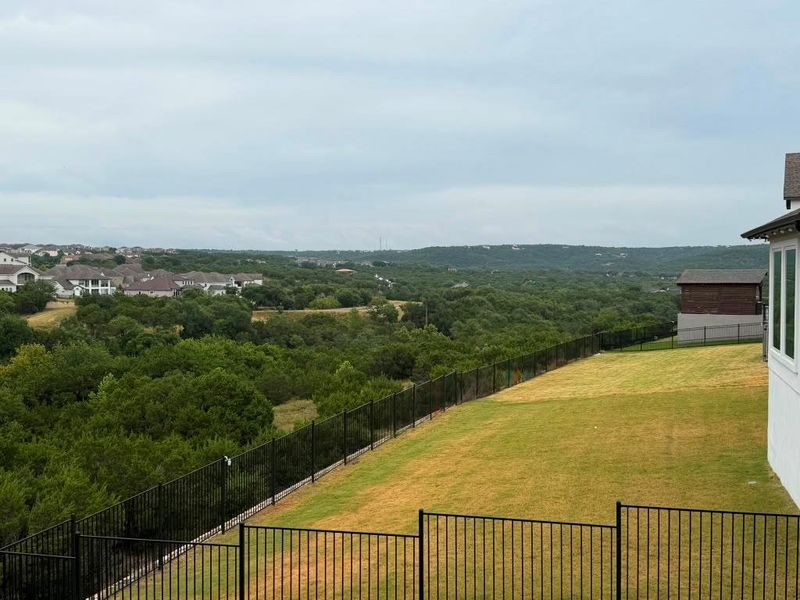 A spacious backyard with mature trees and vast hillside views, ideal for outdoor living.