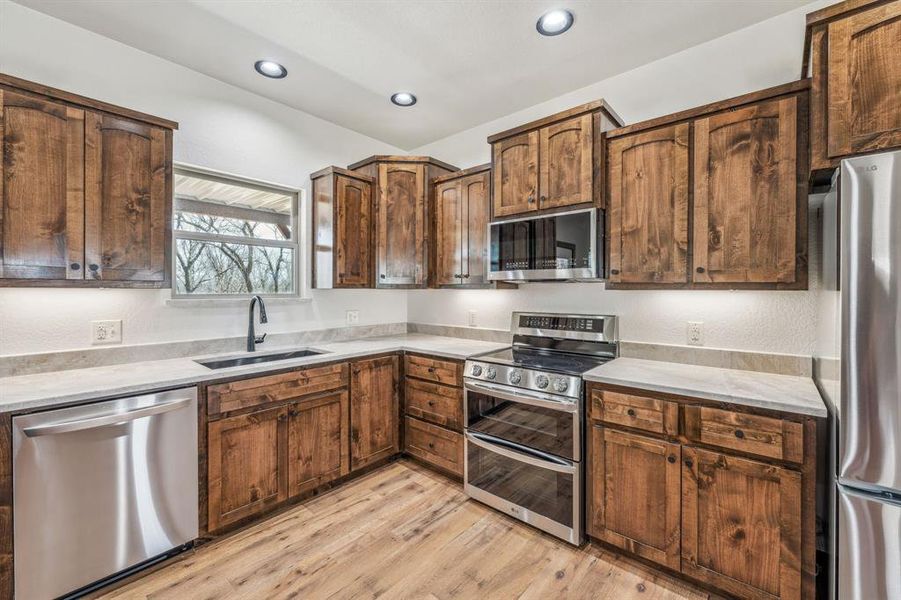 Kitchen featuring light countertops, recessed lighting, a sink, light wood-style flooring, and appliances with stainless steel finishes