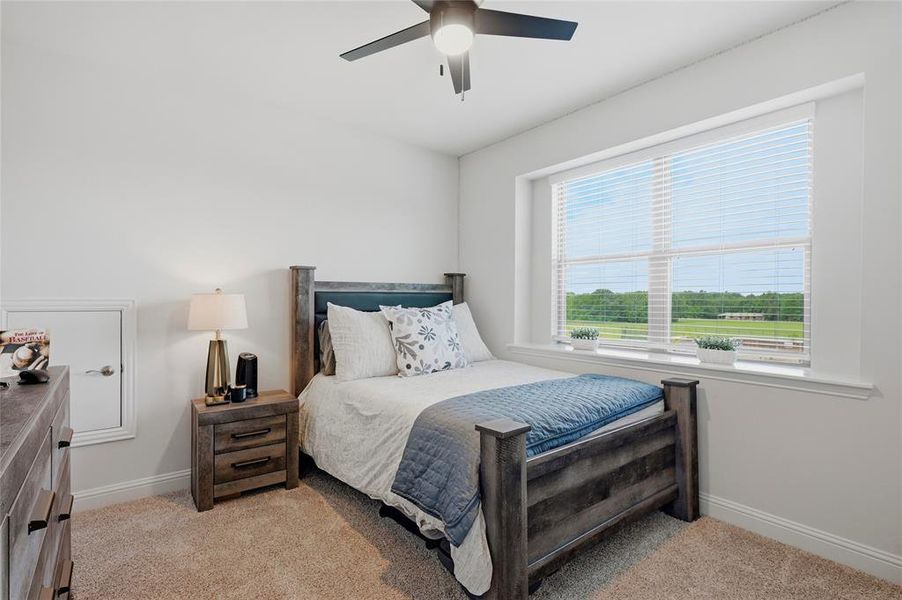 Bright room with a large window, neutral carpeting, and a ceiling fan with integrated lighting
