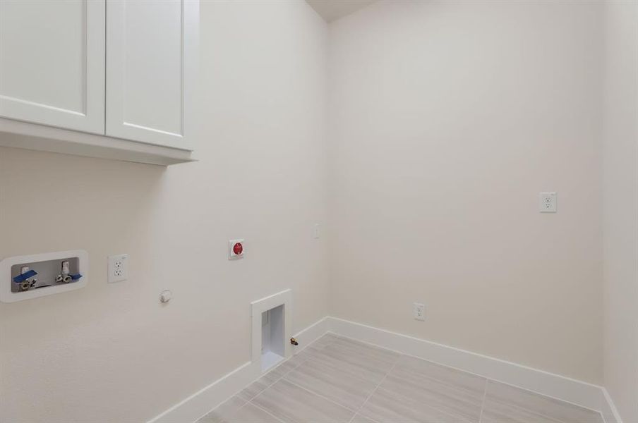 Laundry area with cabinets, hookup for an electric dryer, washer hookup, light tile patterned floors, and gas dryer hookup