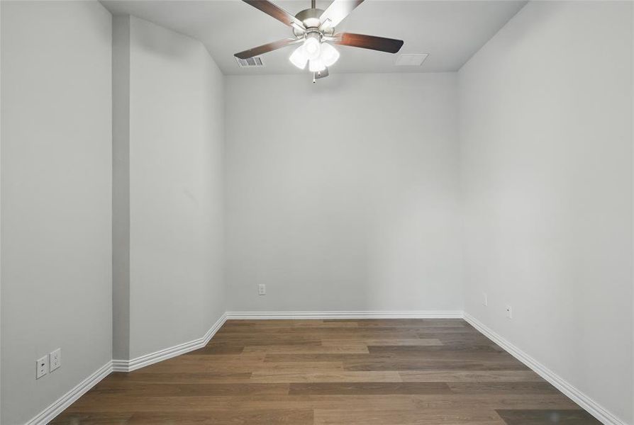 Spare room featuring a ceiling fan, wood finished floors, and baseboards