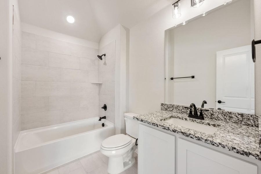 Bathroom with white cabinets, granite countertop, tub-shower combo, and black fixtures
