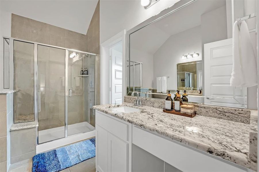 Full bath featuring vanity, a shower stall, and vaulted ceiling