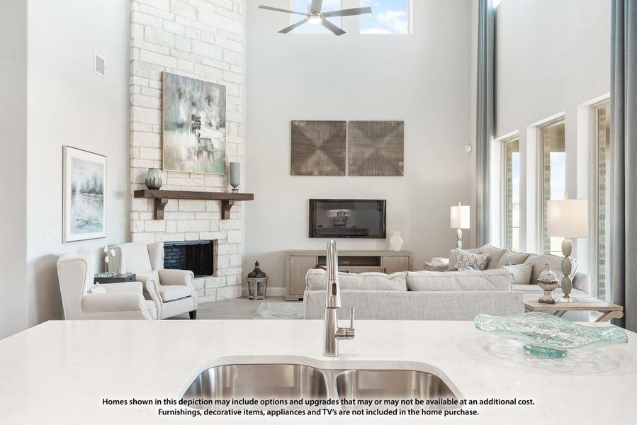 Open-concept living area with white brick fireplace, high ceilings, and kitchen island with stainless steel sink in foreground