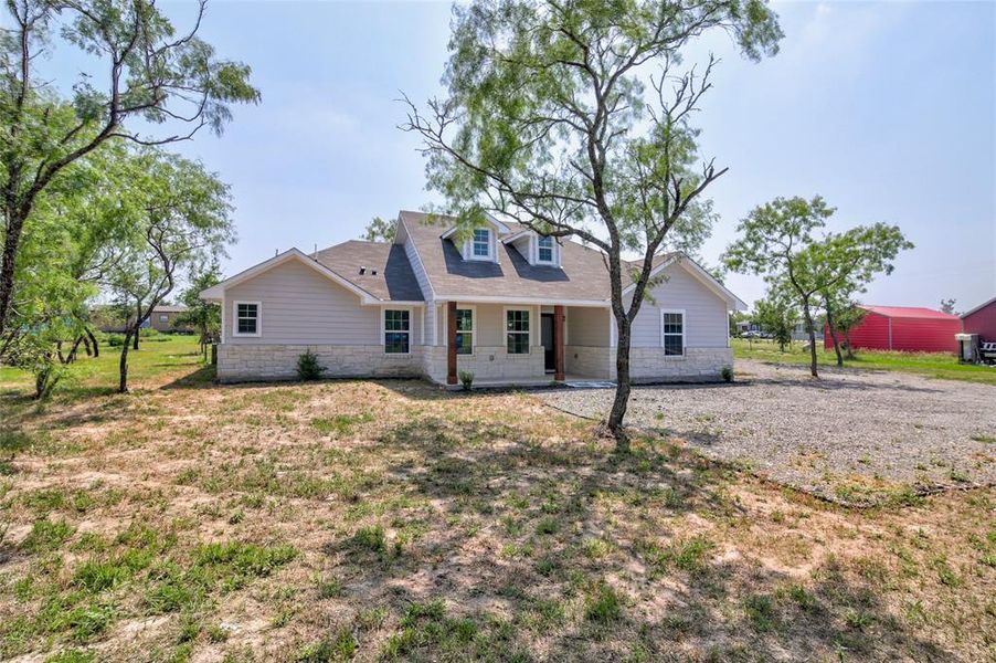 Gorgeous curb appeal with well-crafted architectural design, striking stone masonry, and a welcoming covered front porch with tastefully stained wood pillars.