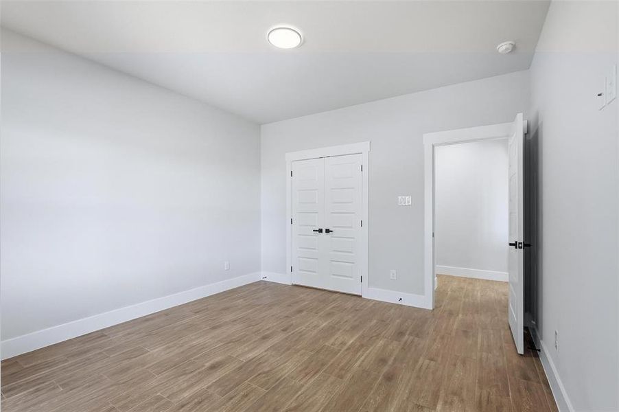 Unfurnished bedroom with wood finished floors and a closet