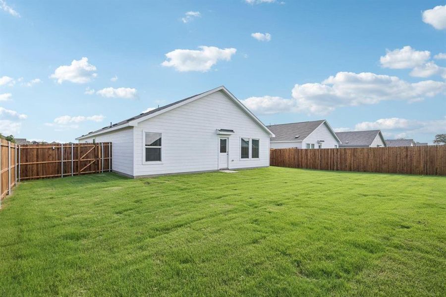 Expansive green lawn with a newly installed wood privacy fence enclosing the property Expansive green lawn with a newly installed wood privacy fence enclosing the property