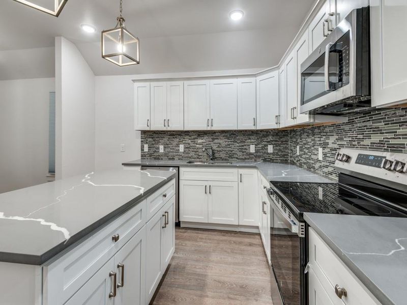 Kitchen with white cabinetry, light hardwood / wood-style flooring, and appliances with stainless steel finishes