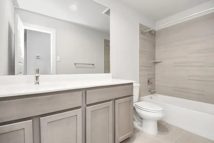 Indulge in refined charm in the secondary bathroom, where the tile flooring harmonizes with a bath/shower combo surrounded by tasteful tile. Light wood cabinets, coupled with a gorgeous countertop, elevate the space, cultivating a truly welcoming atmosphere. Sample photo of completed home with similar floor plan. Actual colors and selections may vary.
