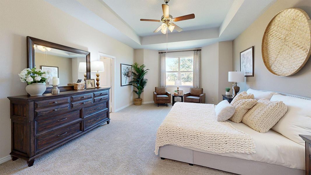 Bedroom with light carpet, a ceiling fan, and a tray ceiling Bedroom with light carpet, a ceiling fan, and a tray ceiling