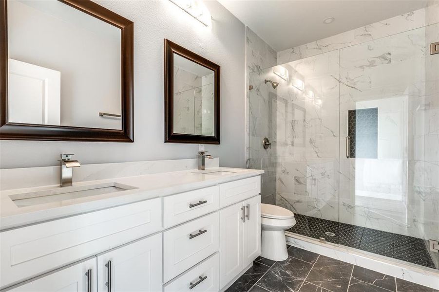 Bathroom with vanity, toilet, and a shower with door