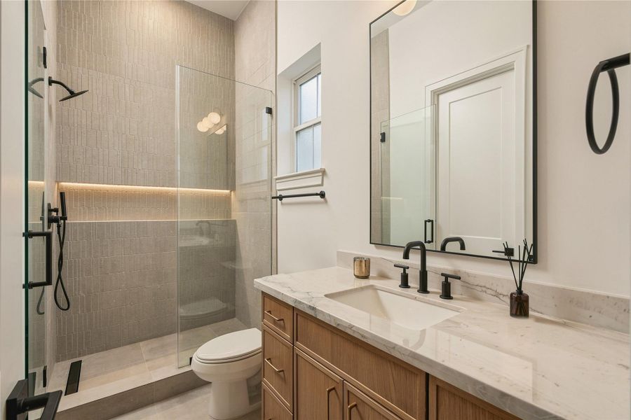 The study is complemented by its own full bath, finished with Mount Blanc Quartzite, designer tile extending to the ceiling, and a frameless glass shower—allowing the space to easily function as a private