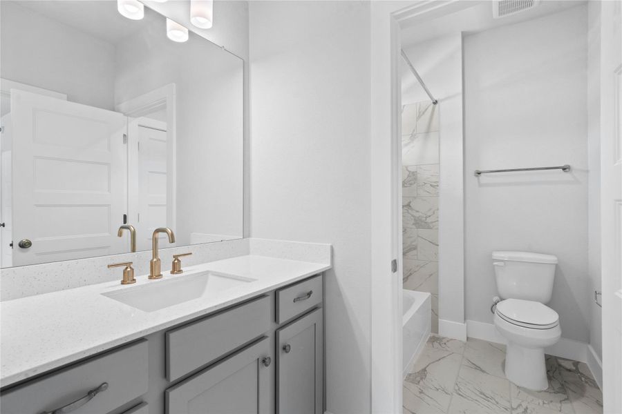 This vanity area is shared with a secondary bedroom and game room. The tub/shower combination with tile surround and toilet are shared with another secondary bedroom.