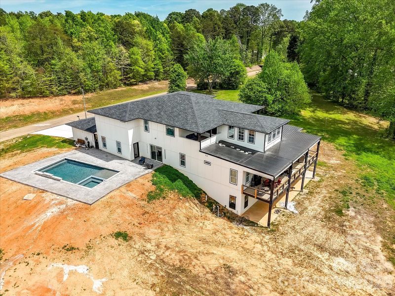 Back of the home featuring a large covered deck, lower-level patio, and expansive yard with plenty of space for outdoor living.
